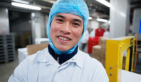 Nhân viên trong trang phục bảo hộ làm việc tại cơ sở chế biến thực phẩm.